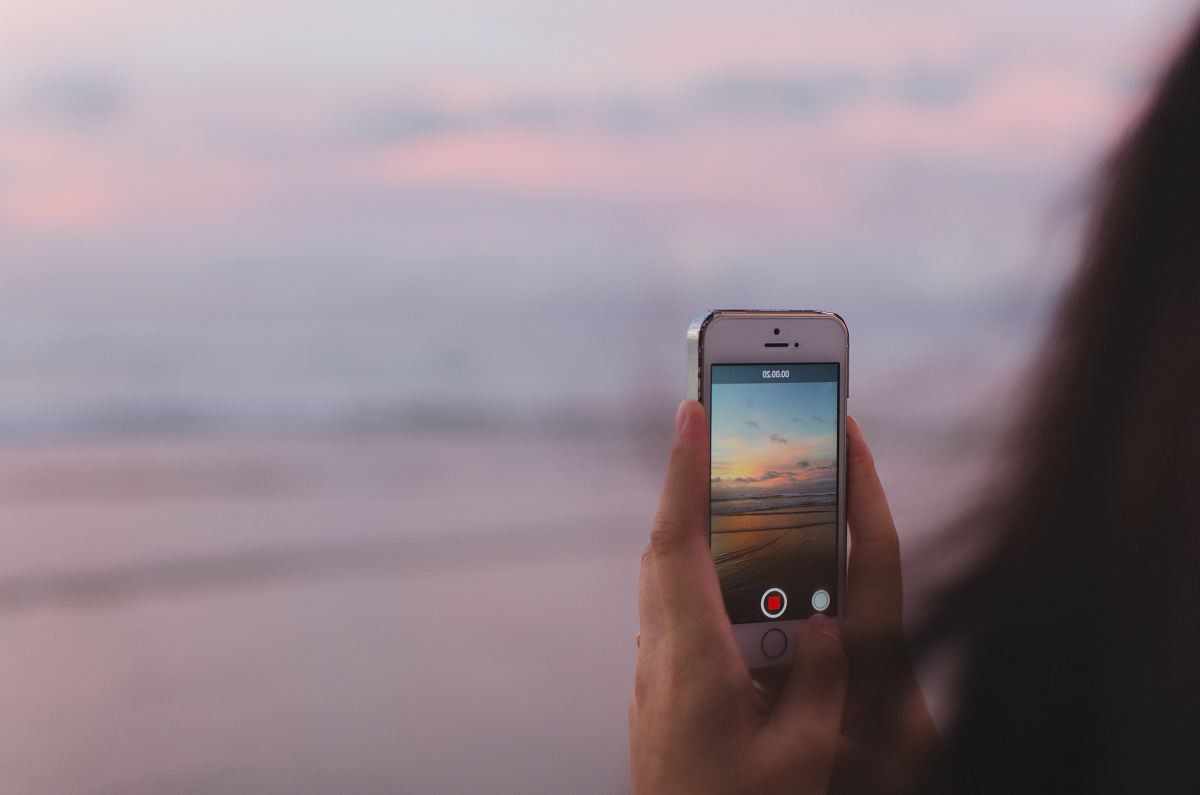 person taking a photo of of open sea and sunset